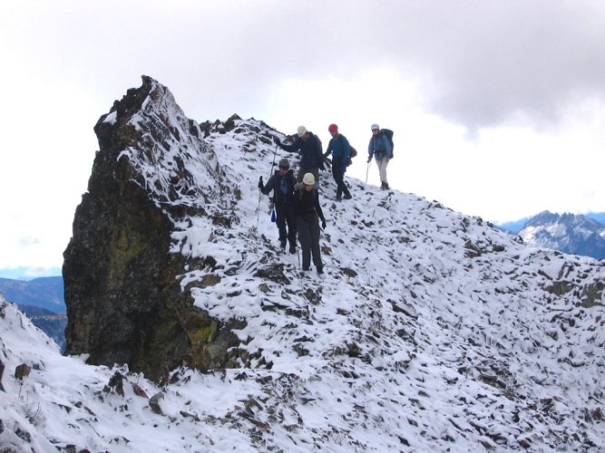 The group is crossing the last hump of snowy rocks.